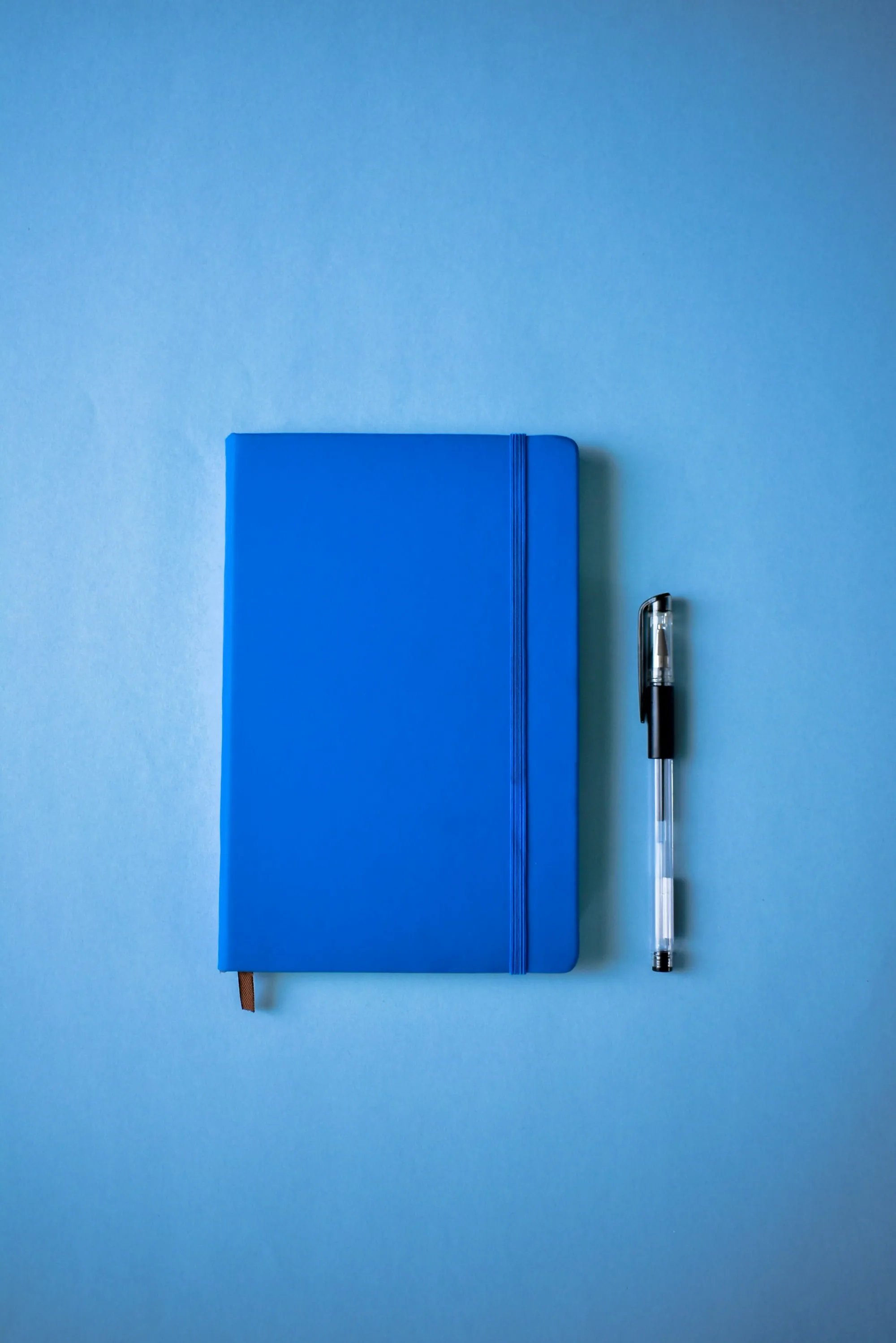 Blue notebook and pen on a blue surface
