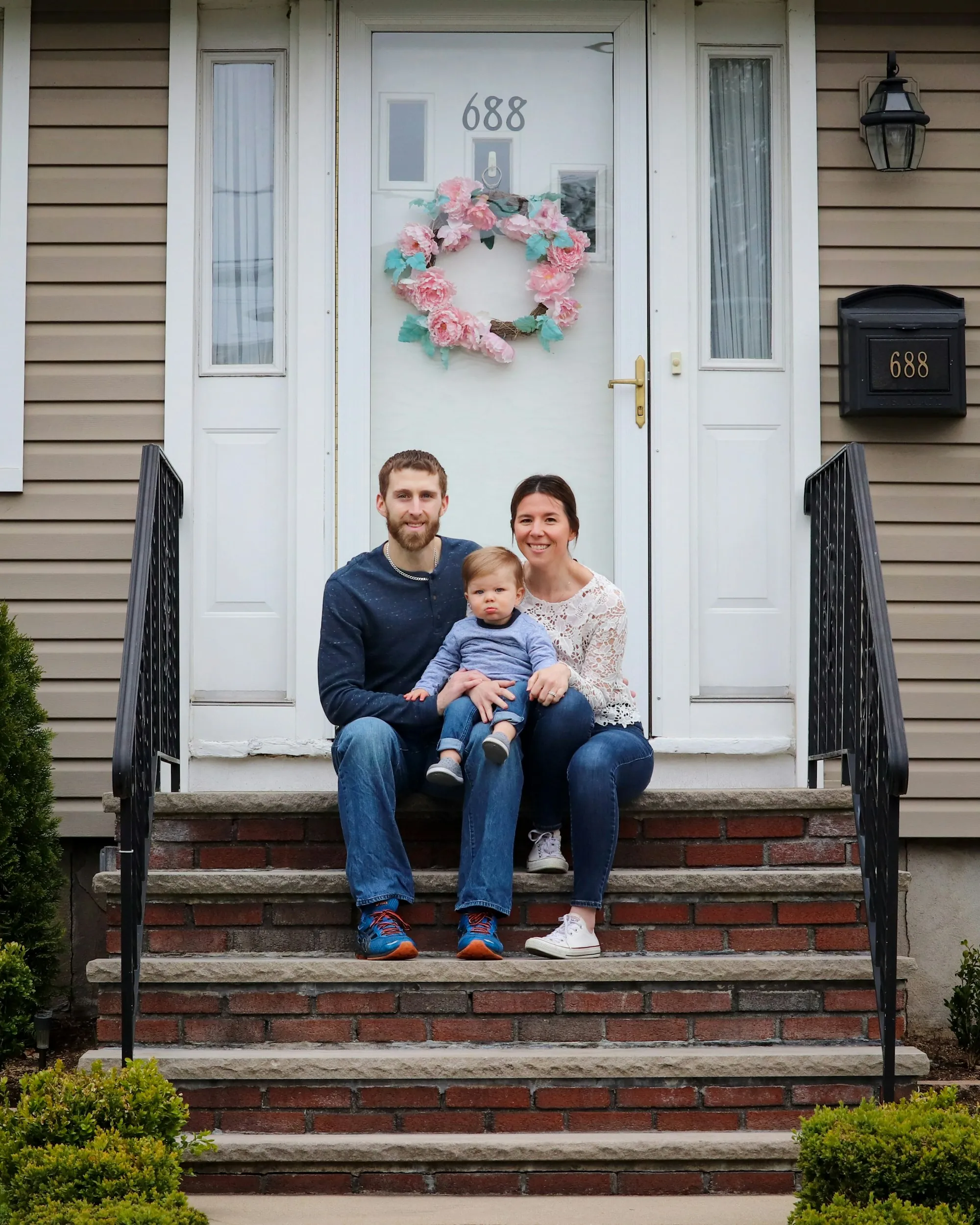 Young family sitting on the front steps of a house