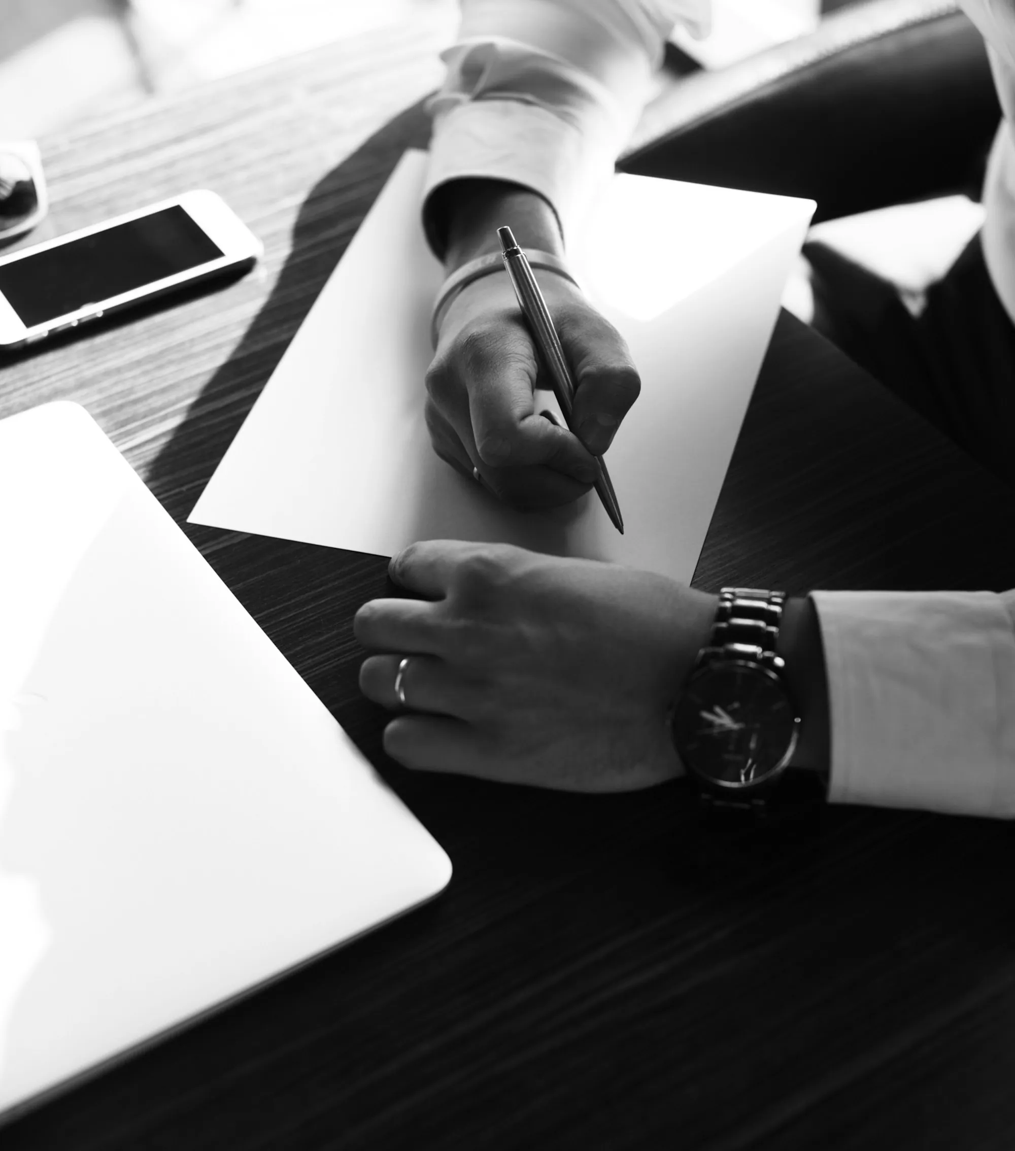 Hand signing papers at a desk