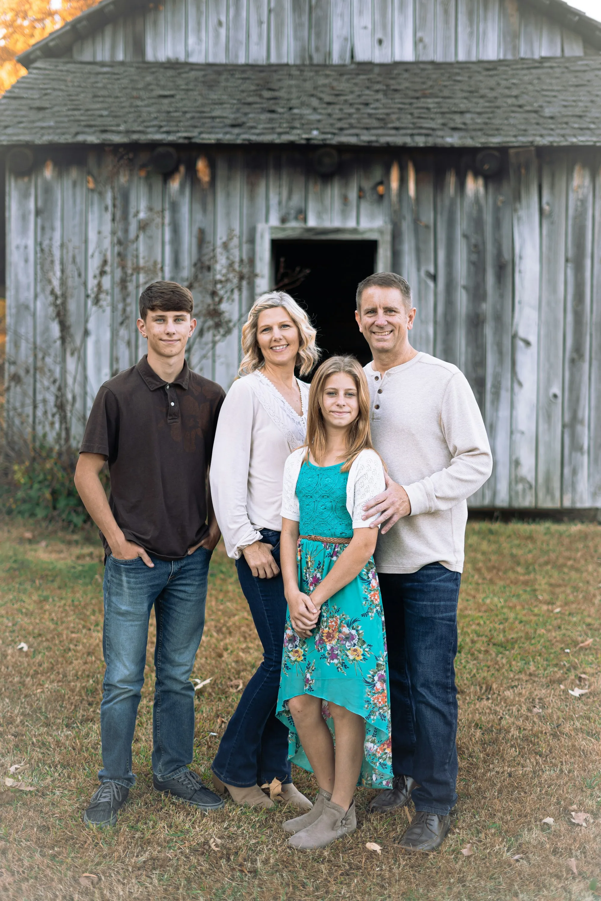 Parents and three teenagers standing in front of a barn